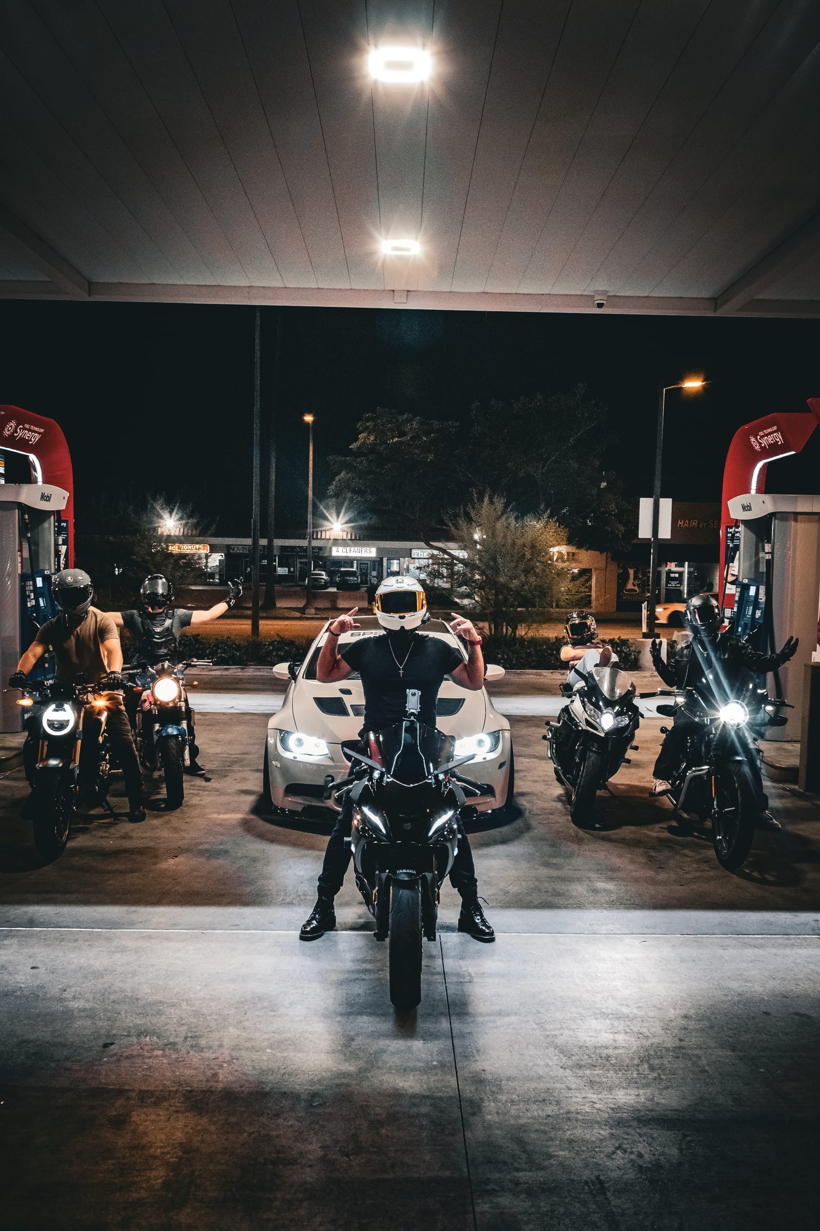 Riders lined up at the pumps, one pointing at the camera