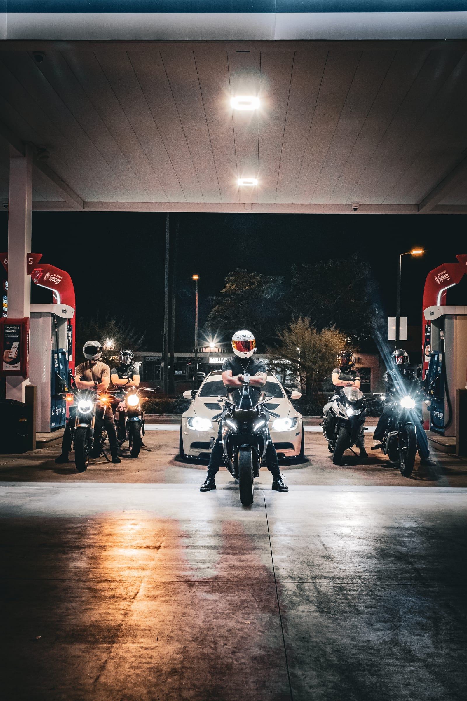 Solace riders lined up under a gas station canopy at night