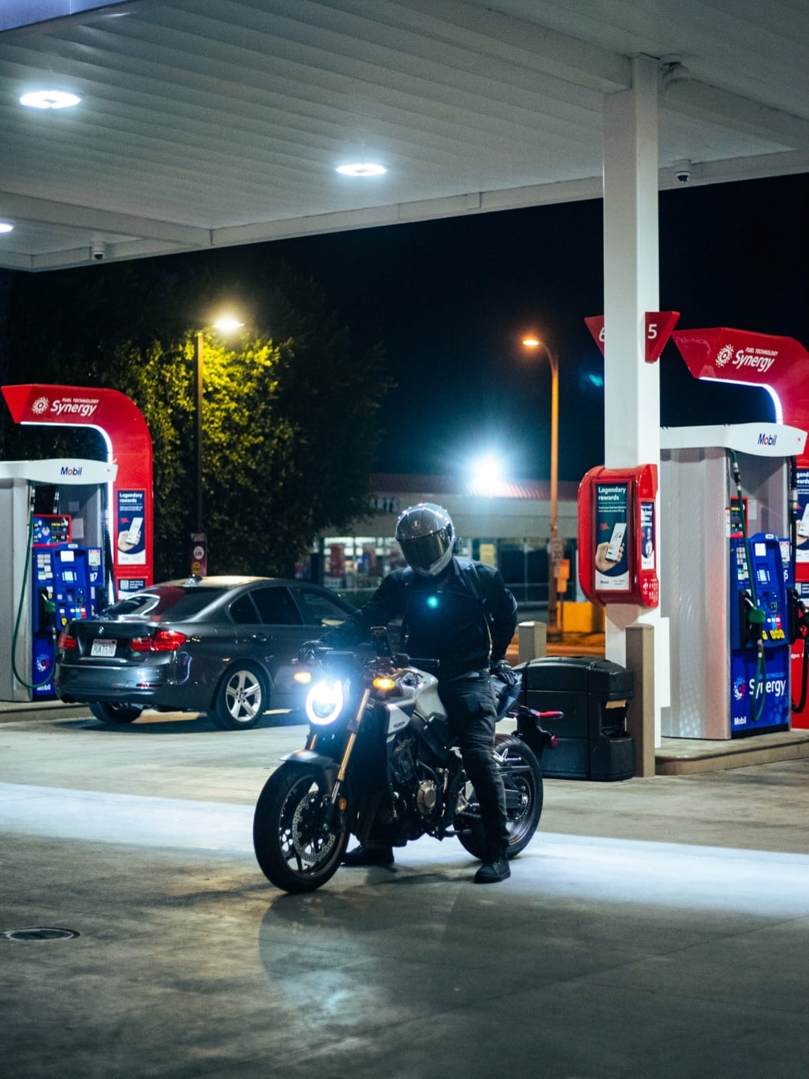 A rider rolls through the pumps, headlight on