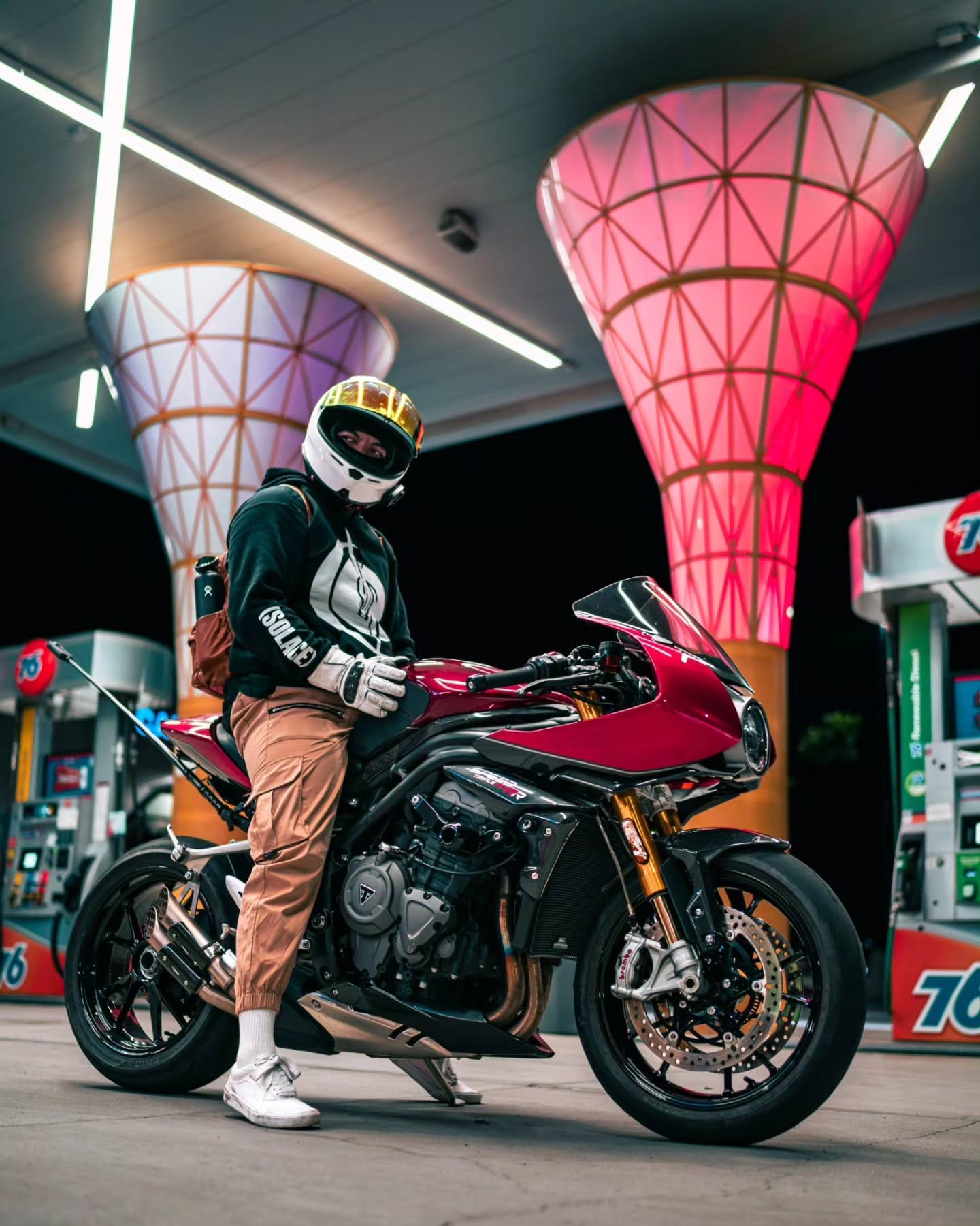 Rider on a red Triumph under the lit canopy columns