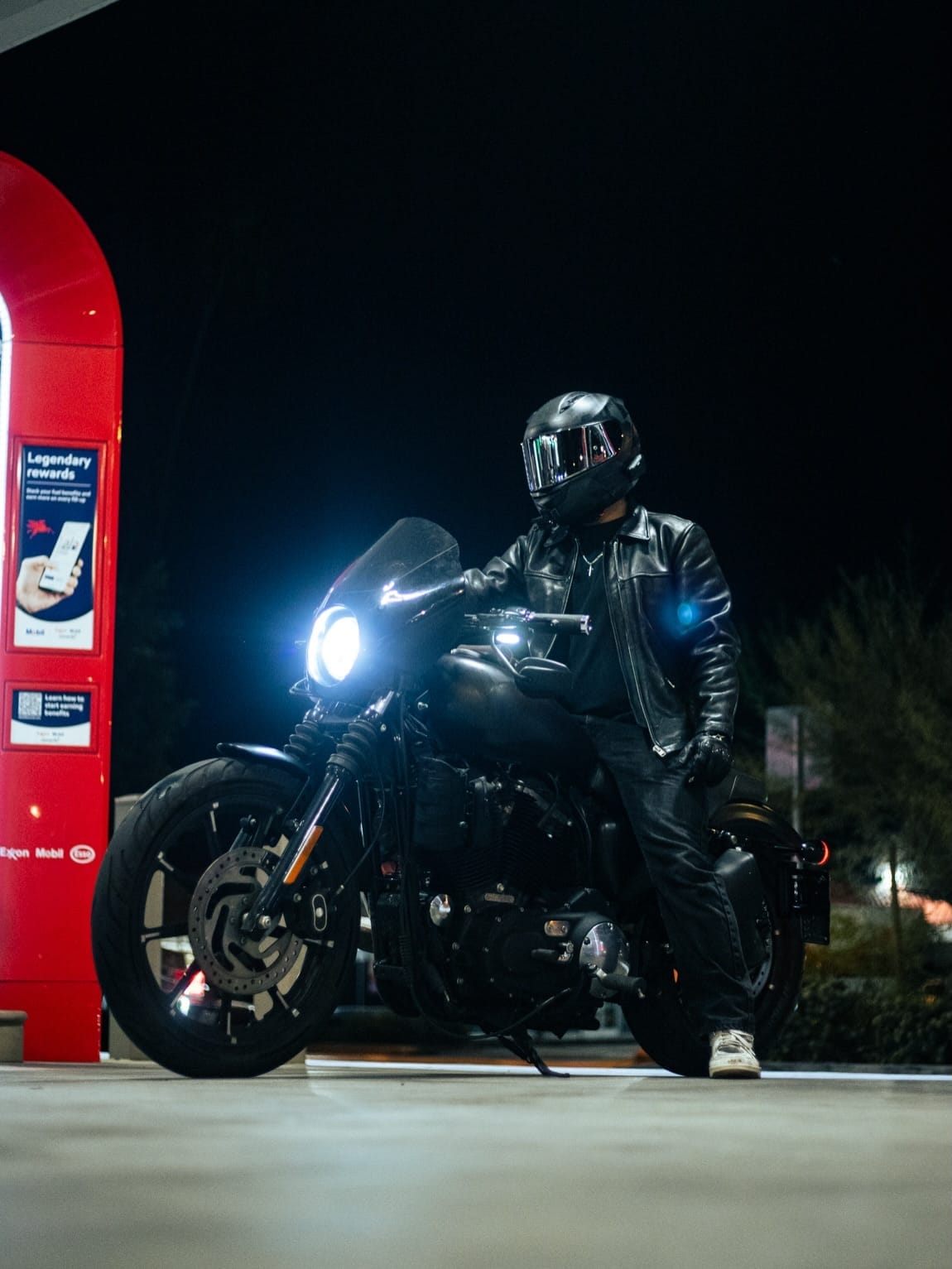 Rider on a dark bike beside a red pump