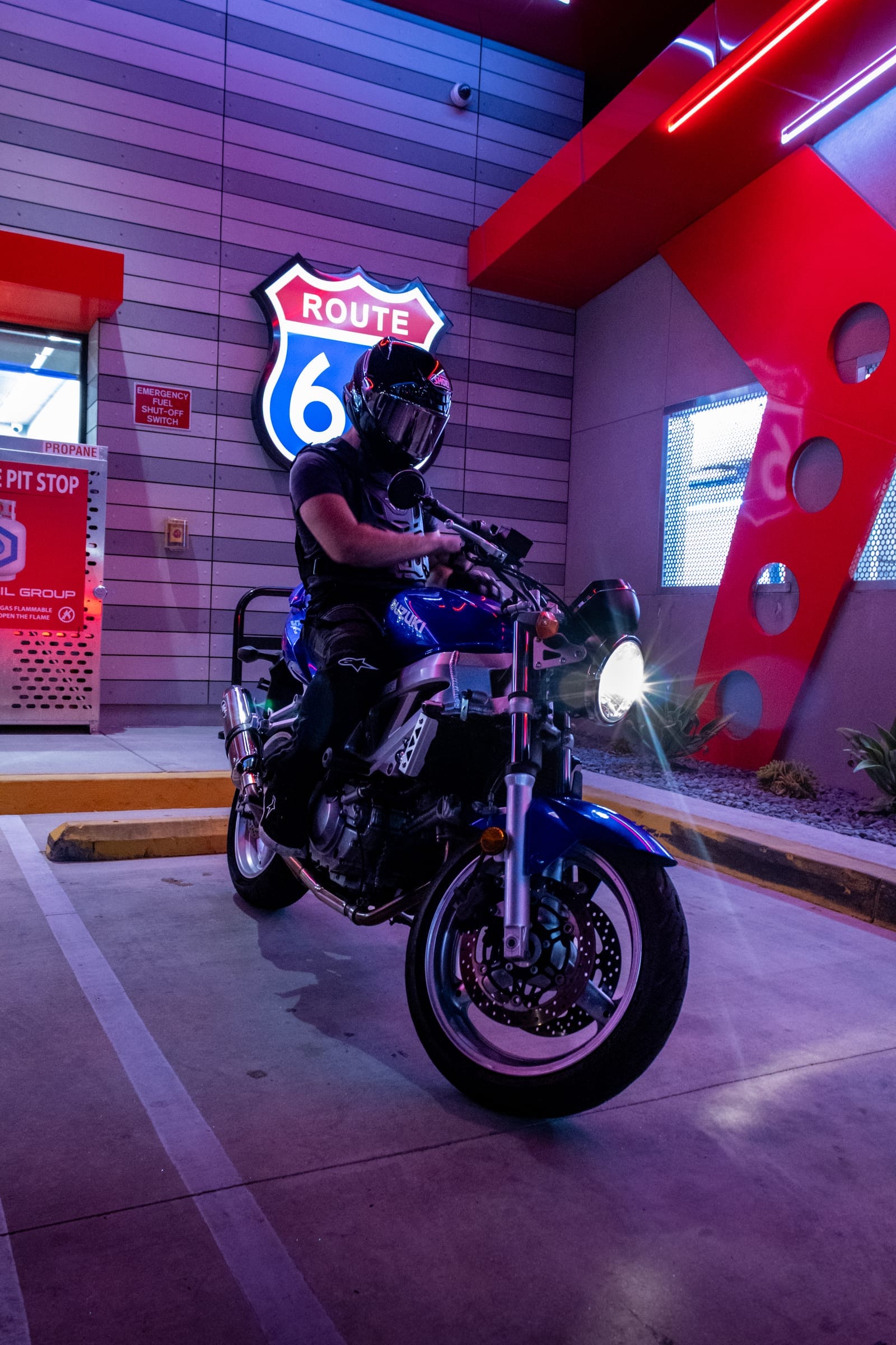 Rider on a blue naked bike under the Route 66 sign, headlight on