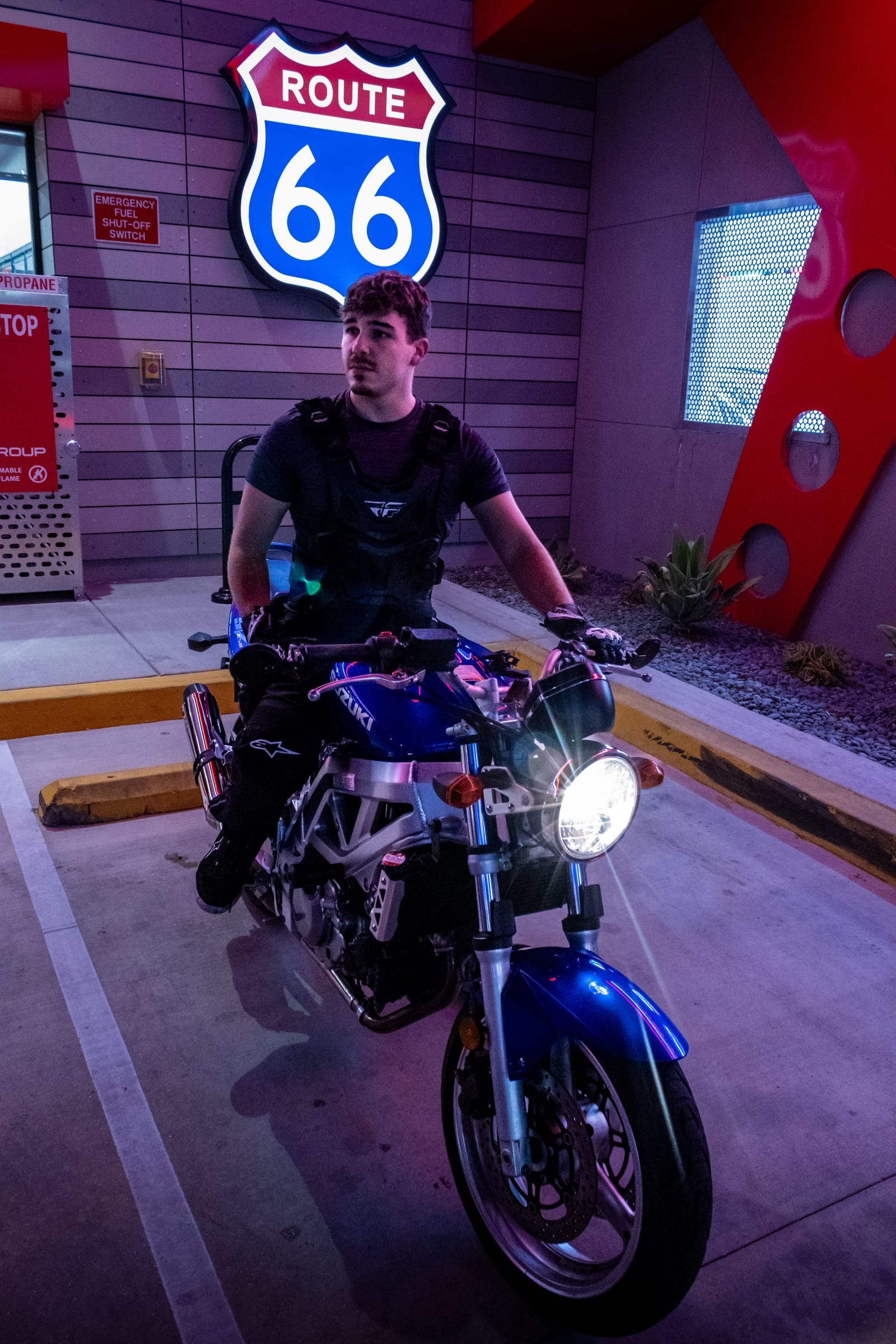 Rider on a blue naked bike against the car wash wall, headlight on
