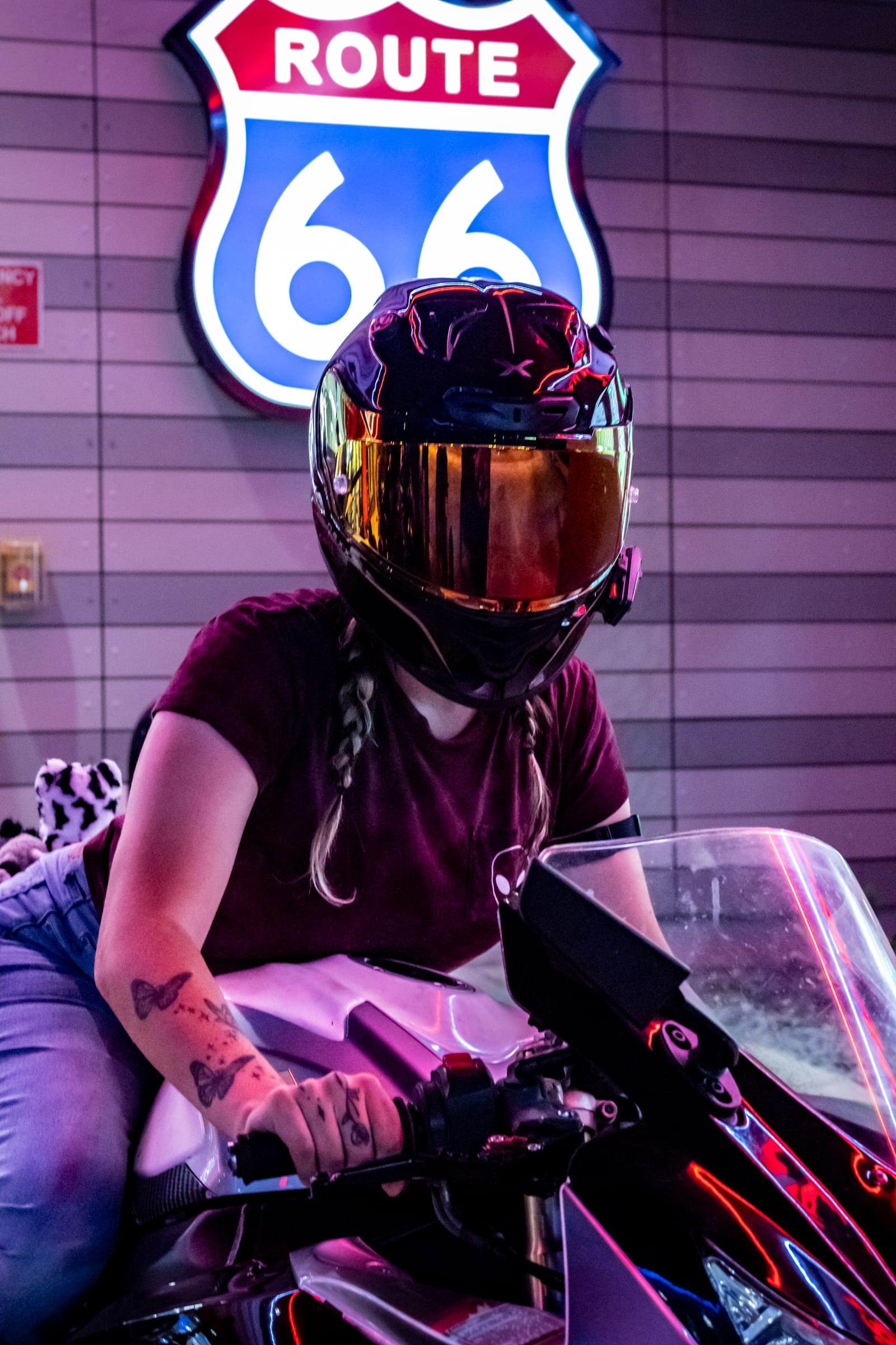 Rider in a gold-visor helmet on a white sportbike under the Route 66 sign
