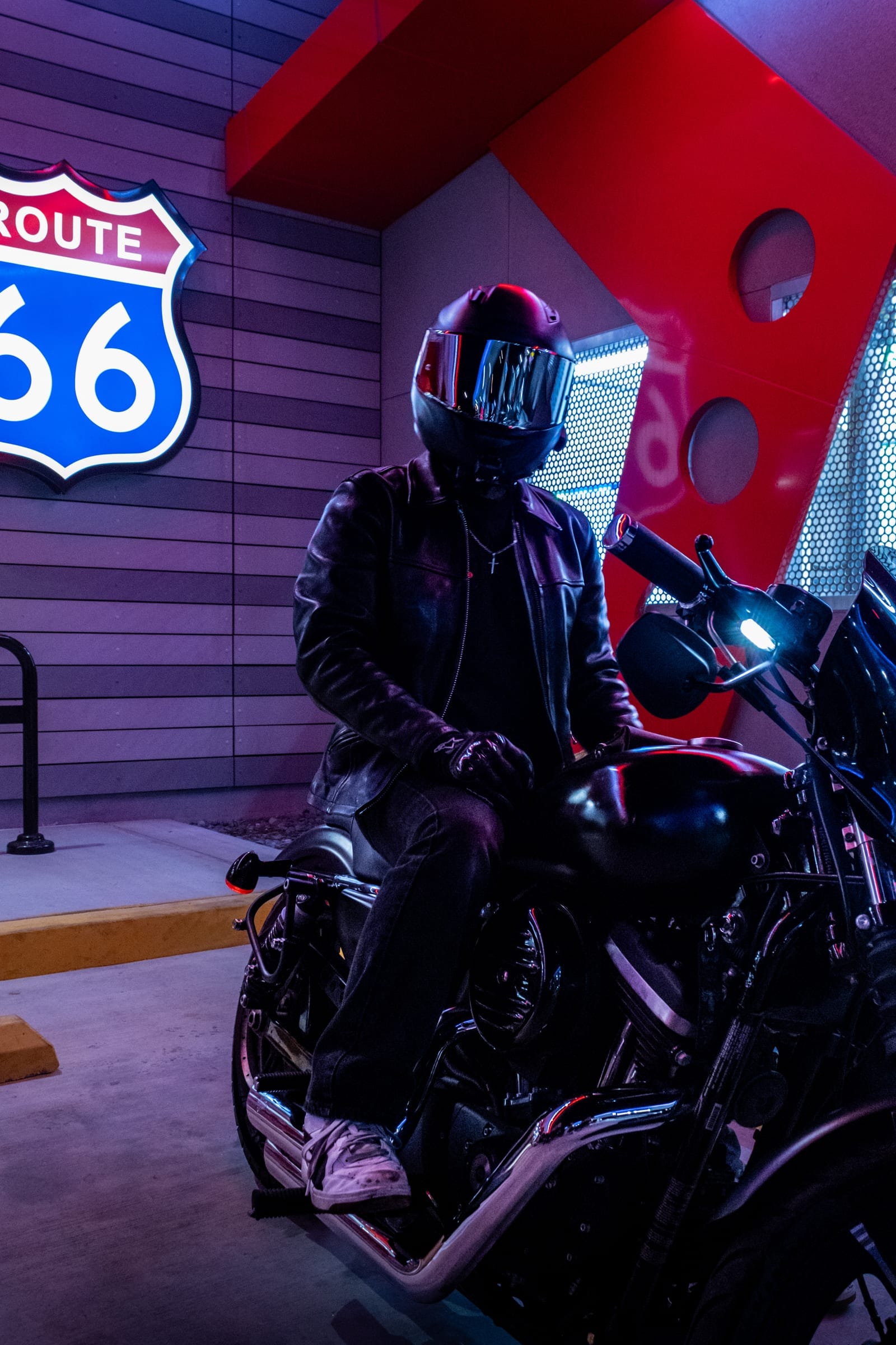 Rider in a leather jacket on a black cruiser under the Route 66 sign