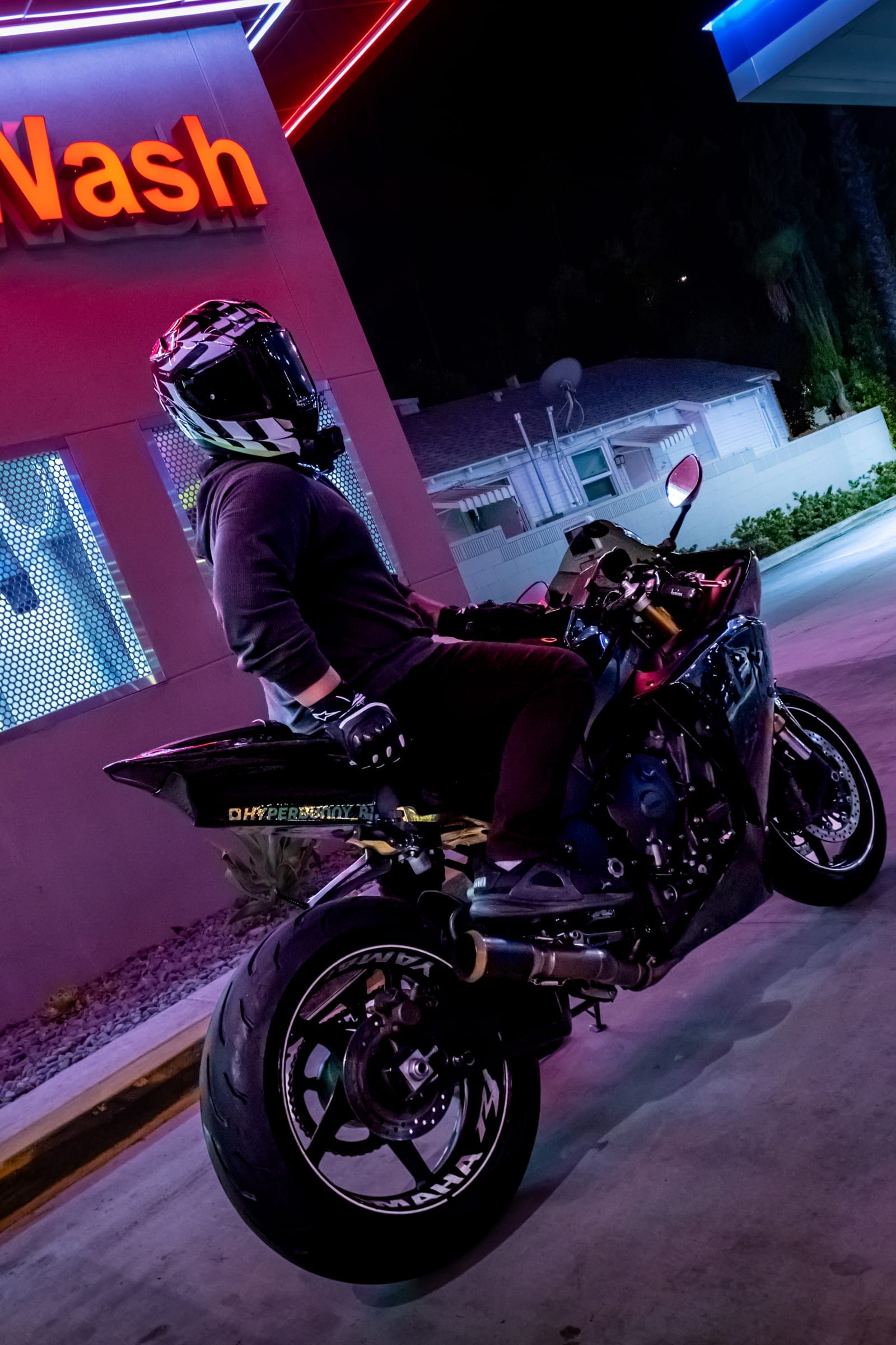 Low angle on a sportbike's rear wheel under the Car Wash sign