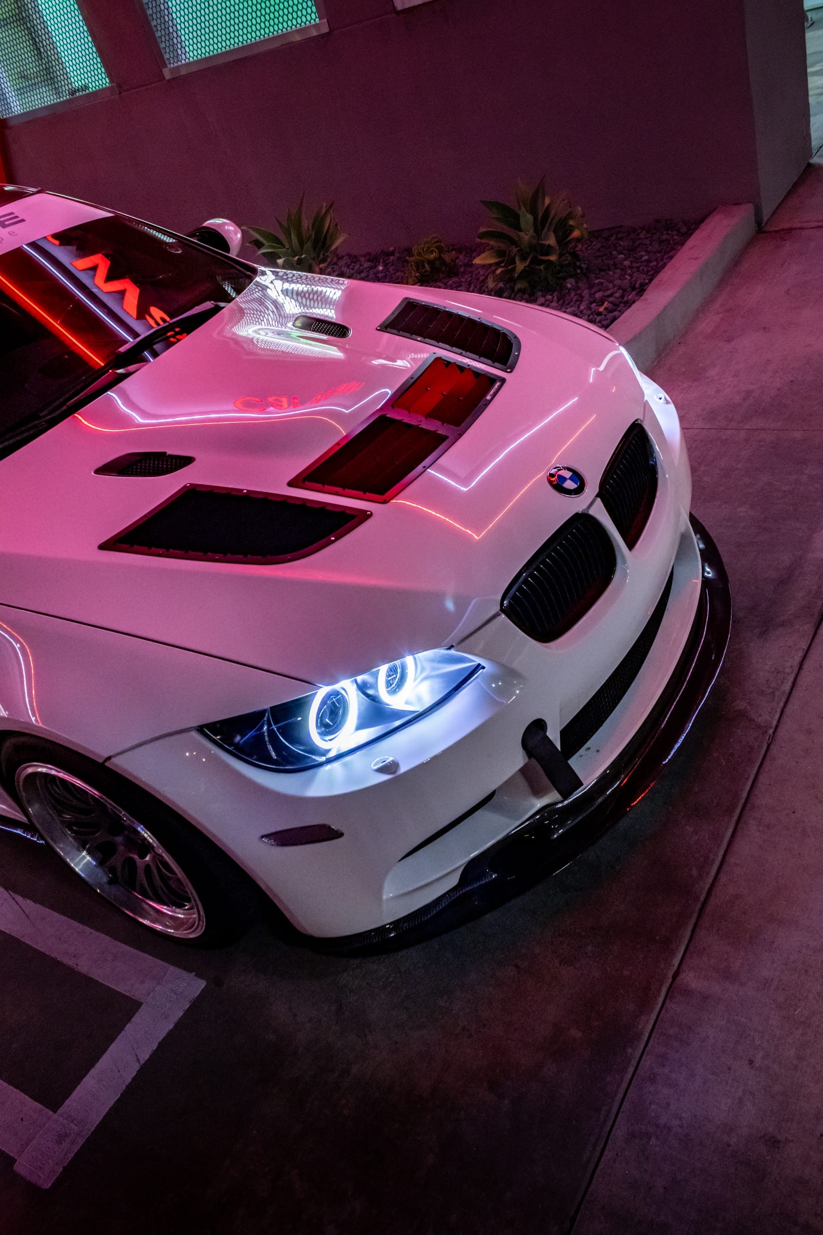 Close-up of the white BMW M3's vented hood and angel-eye headlight