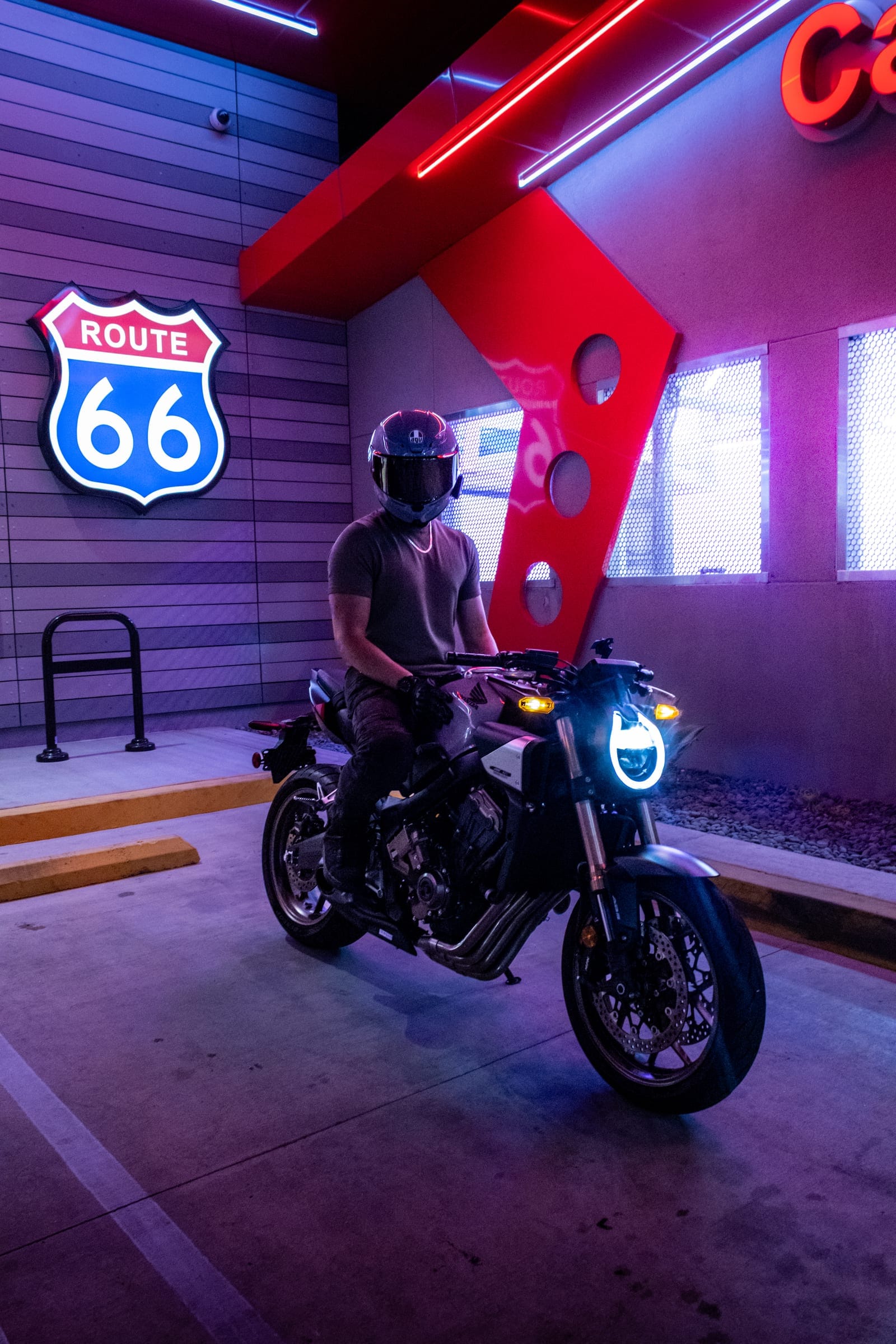 Rider on a naked bike with a round LED headlight against the car wash wall
