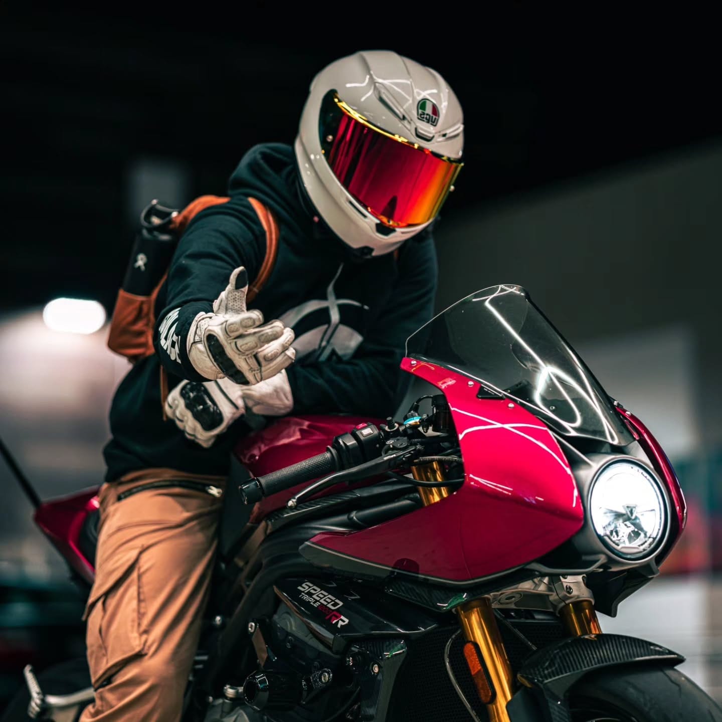 Rider in a Solace hoodie on a red Triumph