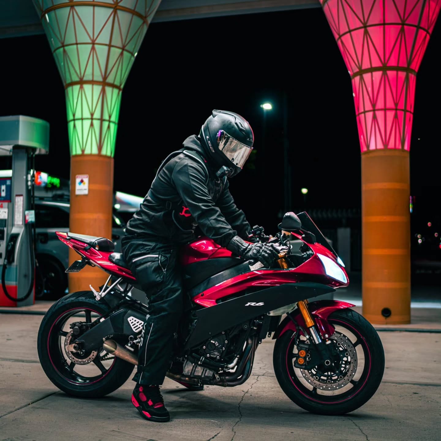 Rider on a red sportbike under lit columns