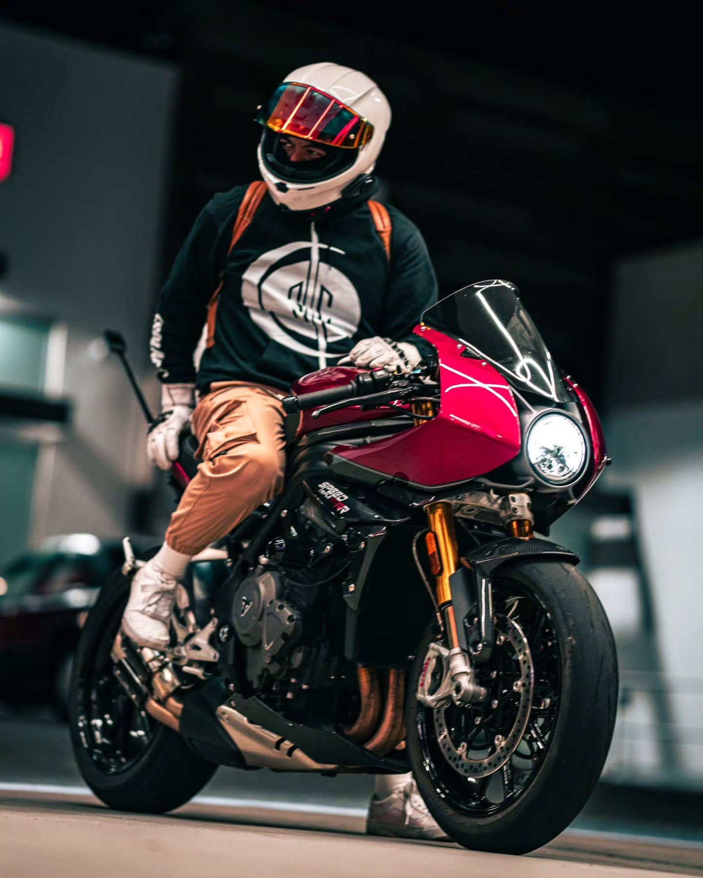 Rider seated on a red Triumph Speed Triple at night